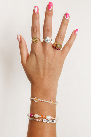 close-up-image-of-a-hand-with-painted-nails-wearing-beaded-bracelets-and-gold-rings-including-that-of-the-spell-s-stargazer-zodiac-ring