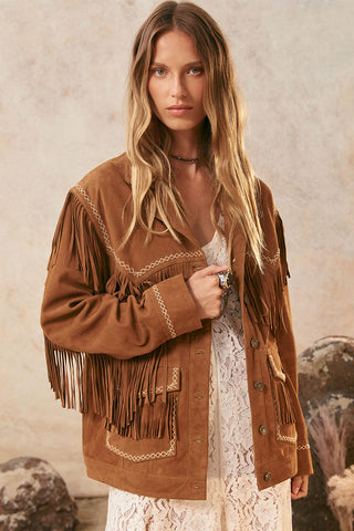 woman-wearing-a-brown-fringed-jacket-against-a-neutral-background