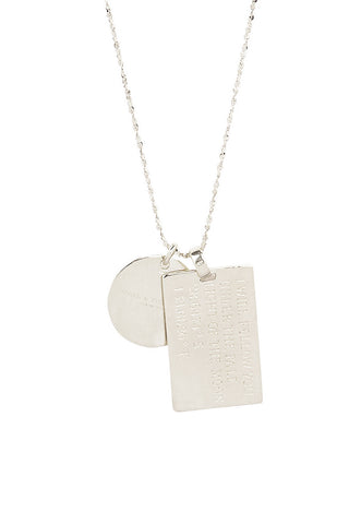 Close up back view of Spell’s Libra Stargazer Zodiac Necklace charms. One charm is of a rectangular shape and an inspirational quote while the other charm is circular the brand name.