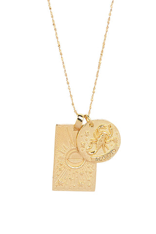 Close up front view of Spell’s Scorpio Stargazer Zodiac Necklace charms. One charm is of a rectangular shape and features a sun with stars while the other charm is circular and features the Zodiac label and icon.